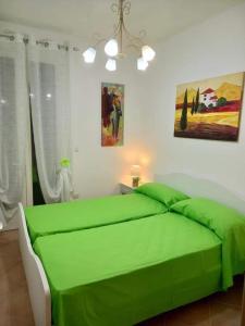 Una cama verde en una habitación blanca con aversión en VILLA ANNA, en Torre Pali