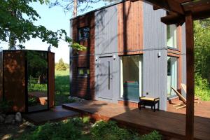 a tiny house with a large door on a deck at SHANTI FOREST HOUSE Guest house with mirror sauna 