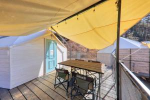 a patio with a table and chairs on a deck at Retreat Camp Mahoroba in Fujikawaguchiko