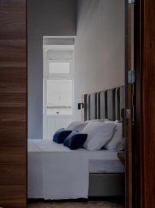 a bedroom with a bed with white pillows and a window at Mulberry Suites in Valletta