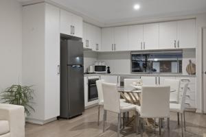 a kitchen with white cabinets and a table and chairs at The Zen Den Retreat Gateway to the Swan Valley in Perth