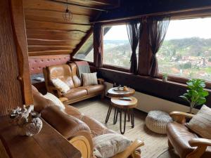 a living room with leather furniture and a large window at Wood house Marilla in Virovitica