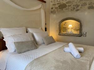 una camera da letto con letto, lenzuola e cuscini bianchi di Malvazia Residence a Kamilari