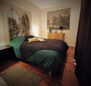 1 dormitorio con cama verde y suelo de madera en Manoir normand du XIVe siecle., en Le Lorey