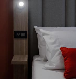 - un lit avec des draps blancs et un oreiller rouge dans l'établissement Mulberry Suites, à La Valette