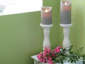 two candles in white candlesticks on a table with flowers at Den lille Skole - Ferie på Ærø i Marstal by in Marstal