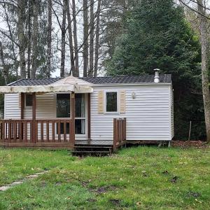 a small white house with a porch in a yard at Camping Onlycamp De La Varenne in Neung-sur-Beuvron