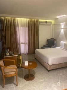 una camera d'albergo con letto, tavolo e sedia di Green House Hotel a As Suways