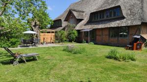 a house with a grass yard with a bench in front of it at FeWo Strohbrück in Quarnbek