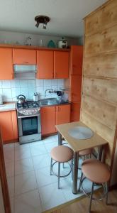 kuchnia z pomarańczowymi szafkami oraz stołem i krzesłami w obiekcie Apartament NEMO we Władysławowie