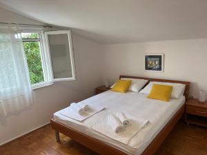 Un dormitorio con una cama con almohadas amarillas y una ventana en Apartments Xenia Pakoštane, en Pakoštane