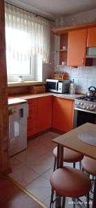 kuchnia z pomarańczowymi szafkami i stołem z krzesłami w obiekcie Apartament NEMO we Władysławowie