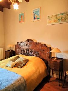 1 dormitorio con 1 cama grande y cabecero de madera en Manoir normand du XIVe siecle., en Le Lorey