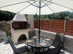 a table with an umbrella on a patio with a fireplace at Domina Villas in Almirida