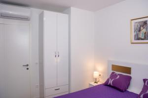 sypialnia z fioletowym łóżkiem i białą szafą w obiekcie Apartman Goldy w mieście Zadar