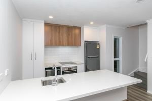 a white kitchen with a sink and a refrigerator at Comfy Stay Close to City Center in Hamilton +4 photos