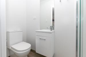 a white bathroom with a toilet and a sink at Comfy Stay Close to City Center in Hamilton