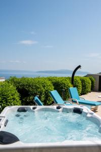 a hot tub with chairs and the ocean in the background at Villa Sveti Petar - with heated pool and outdoor jacuzzi in Opatija