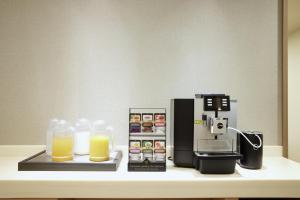 eine Kaffeemaschine und ein Glas Orangensaft auf der Theke in der Unterkunft Sotetsu Fresa Inn Tokyo Kanda in Tokio
