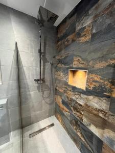 a bathroom with a shower with a stone wall at Romantic Log Cabin With Hot Tub in Leominster
