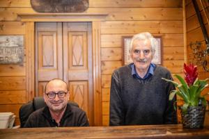 twee mannen aan een tafel in een houten kamer bij Albergo Gran Paradiso in Valsavarenche