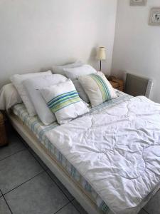 un letto con lenzuola e cuscini bianchi di Appartement T3 climatisé avec vue sur mer a Fleury
