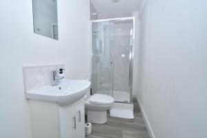 La salle de bains blanche est pourvue d'une douche et de toilettes. dans l'établissement Stay - The Wellington Burton on Trent, à Burton-on-Trent