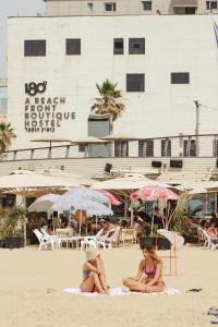 two women in bathing suits sitting on the beach at 180 Boutique Hostel in Tel Aviv