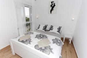 a white bedroom with a bed with flowers on it at Ni-Ka in Pag