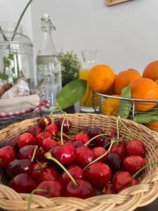 una cesta de cerezas sentada en una mesa con naranjas en Donna Elena, en Vico del Gargano