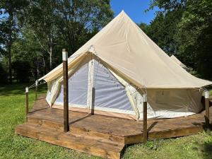 a white tent on a wooden platform in the grass at La Petite Cachette in Pressignac