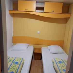 2 camas en una habitación pequeña con paredes amarillas en CAMPING ONLYCAMP LA VARENNE en Neung-sur-Beuvron