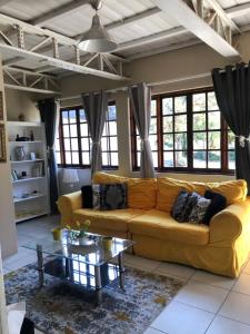 Una sala de estar con un sofá amarillo y una mesa. en Villa Jullienne - A Home Away From Home - Unit 3, en Nelspruit