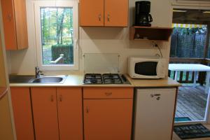 a small kitchen with a microwave and a sink at Camping Onlycamp De La Varenne in Neung-sur-Beuvron