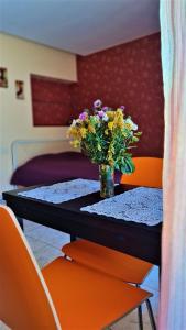 un vase de fleurs assis sur une table avec deux chaises orange dans l'établissement Apartamentai Palangos centre, à Palanga