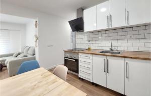 a kitchen with white cabinets and a table and a couch at Nice Apartment In Castell De La Plana With Wifi And 3 Bedrooms in Castellón de la Plana