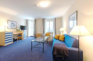 a living room with a blue couch and a desk at Aparthotel Zingst in Zingst