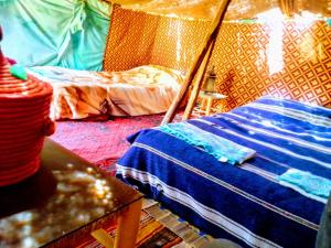 Habitación con tienda de campaña, cama y mesa. en Amoudou Lodge Camp en Tissint