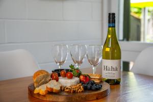 a bottle of wine and a plate of food and wine glasses at Elegant Townhouse in Taupo