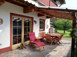 een patio met een tafel en stoelen en een kat ernaast bij Ferienhaus Inntal in Oberaudorf