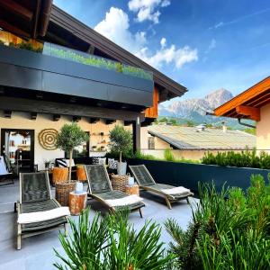 un patio con sedie a sdraio in cima a un edificio di moser-HOCHKÖNIG Genuss Wirtshaus Hotel a Maria Alm am Steinernen Meer