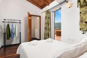 a bedroom with a white bed and a large window at Villa Androniki in Souda