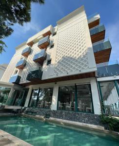 - un bâtiment avec une piscine en face dans l'établissement Hotel Montecarlo - Vista Mare con Area Fitness, à Riccione