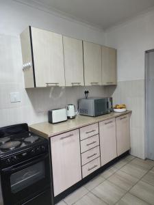 een keuken met een fornuis en een magnetron bij Motebong Villa in Maseru