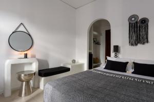 a white bedroom with a bed and a mirror at Aegeeis in Perissa