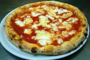 una pizza al formaggio su un piatto bianco su un tavolo di La Collina dei Goti Agriturismo ,Azienda Agricola a Cerreta
