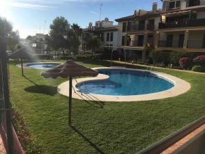 a swimming pool with an umbrella in the grass at Apartamento MG in Ayamonte