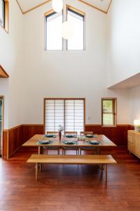 ein großes Esszimmer mit einem Holztisch und Bänken in der Unterkunft LiveGRACE Villa Lake Kawaguchiko 富士河口湖 in Yamanashi