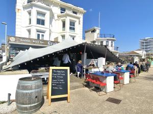 a group of people sitting at tables under a tent at 15 Kingsway House in Worthing