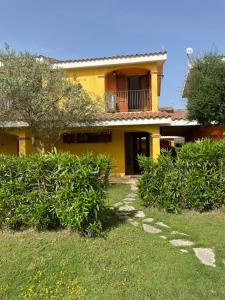 Casa amarilla con balcón y patio en Villa Timo, en SantʼAnna Arresi